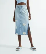 Falda midi de jean celeste con roturas, aberturas laterales y terminación desflecada.