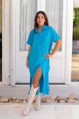 Vestido camisero de muselina color negro, de largo midi, con cuello clásico, manga corta y cierre frontal con botones.