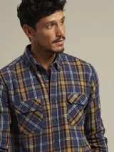 Camisa de cuadros en tonos azules y marrones, con dos bolsillos en el pecho y corte clásico.