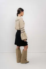 Camisa beige de lino con cuello mao, cierre frontal con botones y detalles de puntilla negra en mangas y frente.