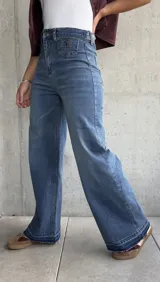 Jean de mujer color azul claro, de corte recto y tiro alto, con bolsillos delanteros decorativos con solapa y botón.