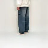 Pantalón jean azul de corte ultra baggy con bolsillos cargo y texto estampado en la pierna izquierda.