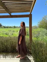 Vestido largo color beige, de corte amplio, con mangas cortas abullonadas y volado en el ruedo.