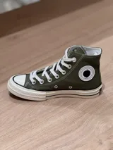 Zapatillas de lona blancas de caña alta con cordones y puntera de goma. Logo de durazno engomado en la base y en la cara interna.