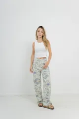 Jean de tiro medio con corte recto y fit relajado, confeccionado en denim estampado con diseño floral en tonos suaves. Cuenta con bolsillos delanteros y traseros, detalle de logo Peach en la parte posterior y cierre con botón metálico y cremallera.