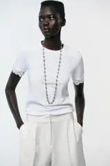 Camiseta blanca de algodón con cuello redondo y mangas cortas con detalle de encaje negro.