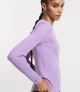 Suéter de punto color verde, con cuello barco, mangas largas y textura acanalada.