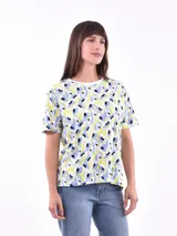Remera estampada con manchas abstractas en amarillo, celeste, blanco y negro, de corte recto y mangas cortas.