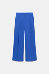 Pantalón azul eléctrico de tiro alto con bolsillos delanteros y falsos bolsillos traseros. Detalle de pliegues frontales y cierre con cremallera y botón.