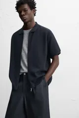 Chaqueta azul marino de tejido con mezcla de algodón, corte relaxed fit, cuello solapa, manga corta y cierre frontal con cremallera.
