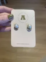Par de aros Aitana con perlas blancas y base plateada con diseño texturizado.