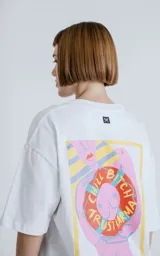 Remera blanca de manga corta con cuello redondo y calce oversize. Presenta una estampa en sublimación inspirada en el tarot, con la imagen de una figura femenina sosteniendo un salvavidas con la frase "Chill Bitch Trust Karma" y el texto "The Wheel of Fortune" en la parte inferior.