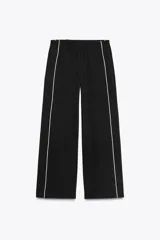 Pantalón negro capri de tiro alto con bolsillos delanteros, cintura elástica y banda lateral blanca a contraste.