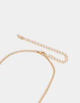Collar corto dorado con cadena de eslabones y dijes colgantes de metal y perlas sintéticas.