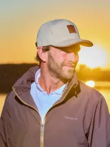 Gorra de gabardina color gris con visera curva y aplique de cuero con logo en el frente. Ajuste trasero con hebilla metálica.