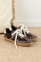 Zapatillas bajas de cuero color marrón oscuro con detalles en blanco y suela de goma color caramelo.