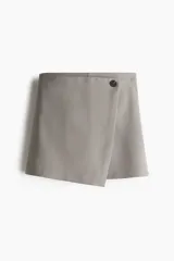Short pollera evasé color gris, en sarga con frente cruzado cosido y botón adelante. Cierre oculto y botón en un lateral.