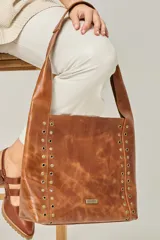 Cartera tipo shopper color negro, con apliques de tachas plateadas en los laterales y logo de la marca en la parte inferior.