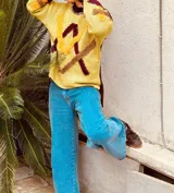 Sweater de punto color pistacho y marrón chocolate, con cuello alto y diseño geométrico bordado en el frente.