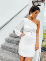 Vestido corto blanco con un hombro descubierto y una manga larga abullonada. Incluye cinturón con hebilla de alpaca y nácar.