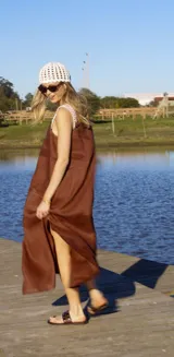 Vestido blanco de lino con breteles de cuero extraíbles mediante botón y ojal, corte suelto y tajos a los costados.