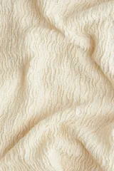 Pantalón de corte holgado color crema, confeccionado en tejido de punto con textura. Modelo de tiro alto con cintura elástica y piernas rectas.
