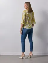 Blusa de gasa verde con estampado de flores blancas y celestes. Tiene cuello a la base con escote en V y mangas 3/4 fruncidas.