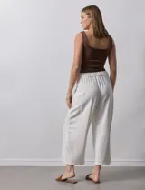 Pantalón de lino color crudo, de corte ancho y tiro alto, con bolsillos laterales y cintura elástica.