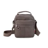 Morral de tela canvas color marrón, con correa regulable, asa de mano, cierre superior, dos bolsillos frontales con cierre, llavero exterior, bolsillos internos y bolsillo trasero con cierre.