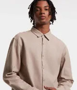 Camisa beige de tricolina texturizada, corte amplio, manga larga y abotonada al frente.