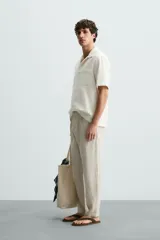 Pantalón de vestir blanco, confeccionado en lino, de corte recto, con bolsillos laterales y traseros. Se ajusta a la cintura con botón y cierre.