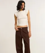 Pantalón recto loose confeccionado en sarga de algodón BCI color marrón, con bolsillos delanteros y traseros, cierre con botón y cremallera.