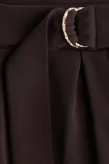 Pantalón sastrero marrón chocolate de punto, tiro alto con elástico oculto en la cintura y cierre decorativo. Cinturón cosido con anillas en D de metal en un lateral. Piernas ajustadas con pinzas para estilizar la silueta.