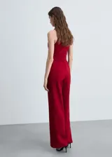 Mono largo color rojo con escote halter cruzado, cinturón con hebilla y pantalón palazzo.