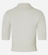 Blusa de punto color crema, con cuello polo, mangas cortas y puños con botones.