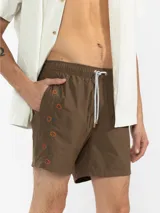 Short de baño marrón con bordado de enredadera en la pierna, cintura elástica con cordón regulable, bolsillos laterales y trasero con cierre.