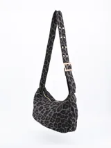 Cartera bandolera con estampado animal print en tonos grises y negros. Tiene correa corta ajustable con hebilla dorada y cierre superior con cremallera dorada.