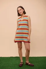 Vestido corto sin mangas con estampado de rombos en amarillo, azul y rojo. Tiene escote con abertura en forma de gota y ruedo con terminación en picos.