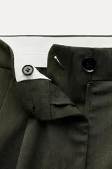 Bermuda larga color verde oscuro de tiro medio y pierna ancha. Confeccionada en hilatura con 19% de lana. Presenta trabillas en la cintura, bolsillos laterales y con solapa en la espalda, pinzas en el delantero y cierre frontal con cremallera y botones.