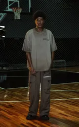 Remera de manga corta y cuello redondo, calce oversize, color marrón oscuro con efecto batik/lavado. Presenta un pequeño bordado o aplique con la palabra "RAVERS" en el pecho.