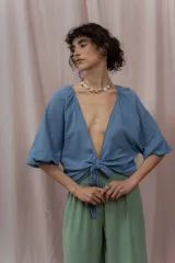 Blusa color mostaza de lino, con escote en V y mangas cortas abullonadas. Se ata en la parte delantera con dos cordones.