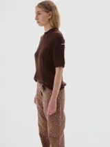 Remera de punto negra con cuello redondo y mangas cortas. Presenta un diseño de tejido con trenzas verticales.