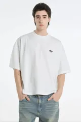 Remera blanca de corte amplio con logo pequeño bordado en el pecho.