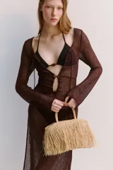 Bolso de mano tipo shopper confeccionado en paja de papel color natural con efecto desflecado. Tiene dos asas trenzadas y no está forrado.