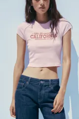 Camiseta rosa de algodón y modal, corte slim fit, cuello redondo, manga corta y largo crop. Estampado frontal con la frase "Old Sacramento CALIFORNIA UNITED STATES, EST. 1974" en color marrón.
