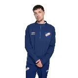 Buzo de entrenamiento Umbro color azul con cierre a la mitad del pecho, escudo del Club Nacional de Football bordado en el pecho izquierdo y logo de Umbro bordado en el pecho derecho.