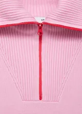 Sweater de punto rosa con cuello alto y cierre de cremallera roja. Diseño recto y manga larga.