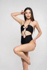Traje de baño enterizo negro con aberturas en el abdomen y escote halter con tiras cruzadas.