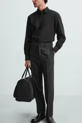 Camisa negra de manga larga, corte slim fit, con cuello italiano y cierre frontal de botonadura.