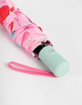 Paraguas corto plegable color rosa con estampado de cerezas, moños y estrellas.